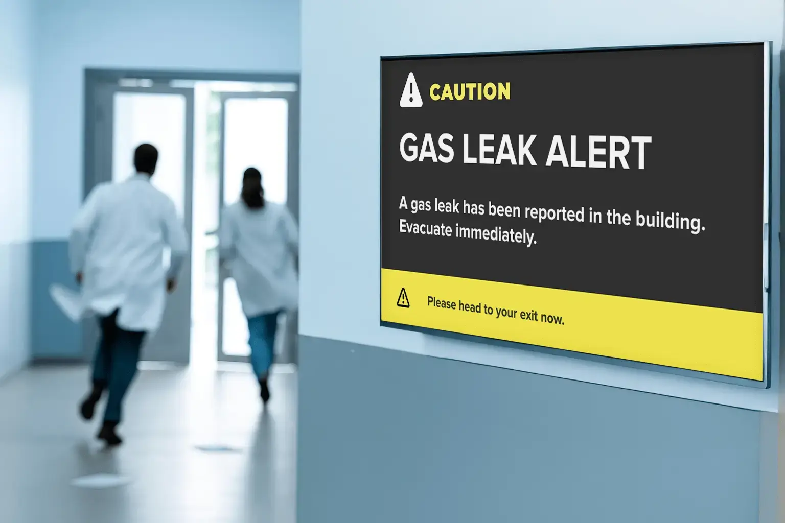 Doctors in a hospital evacuating frantically as digital signage indicates an emergency alert for gas leak