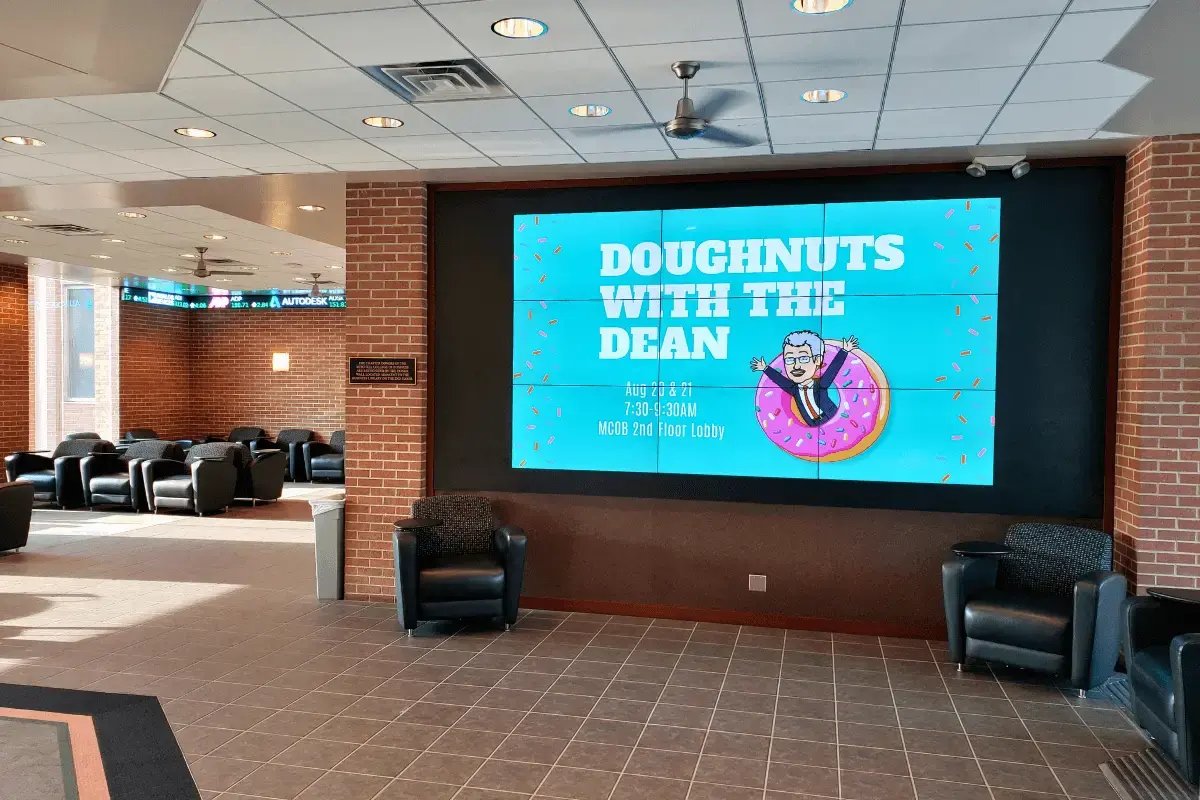 A large multi screen display mounted within brick walls in a university campus