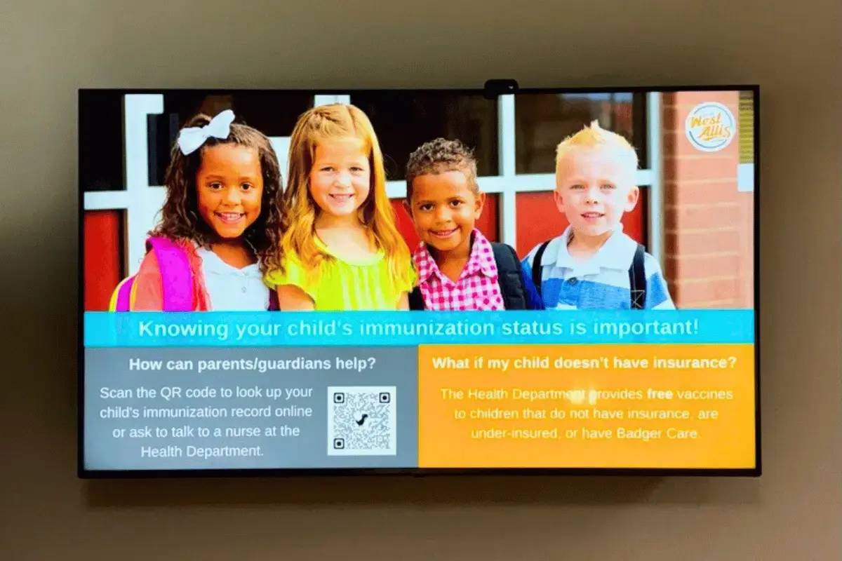 A large digital display with four children on the image and a QR code
