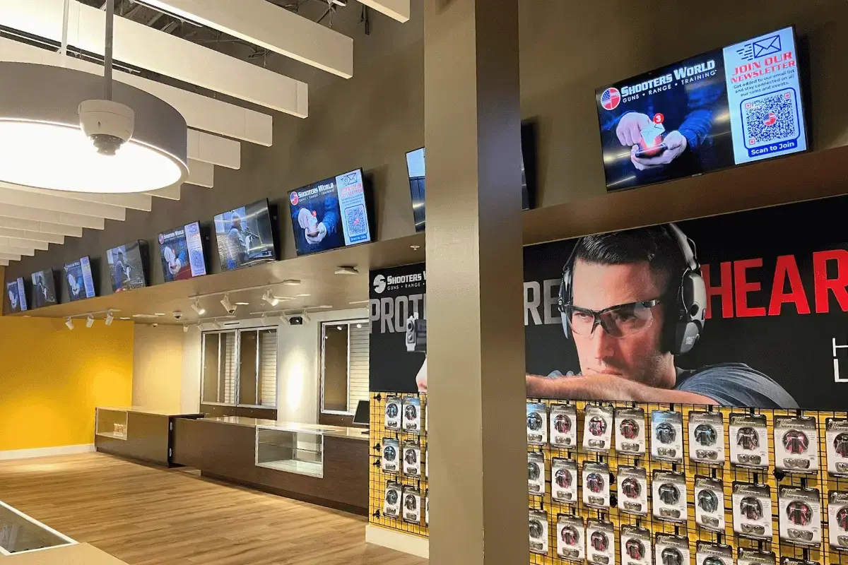 A shooting range with digtial displays on the wall throughout with safety tips