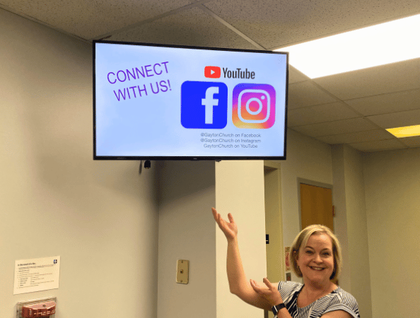 A woman standing in front of a digital display with social media content