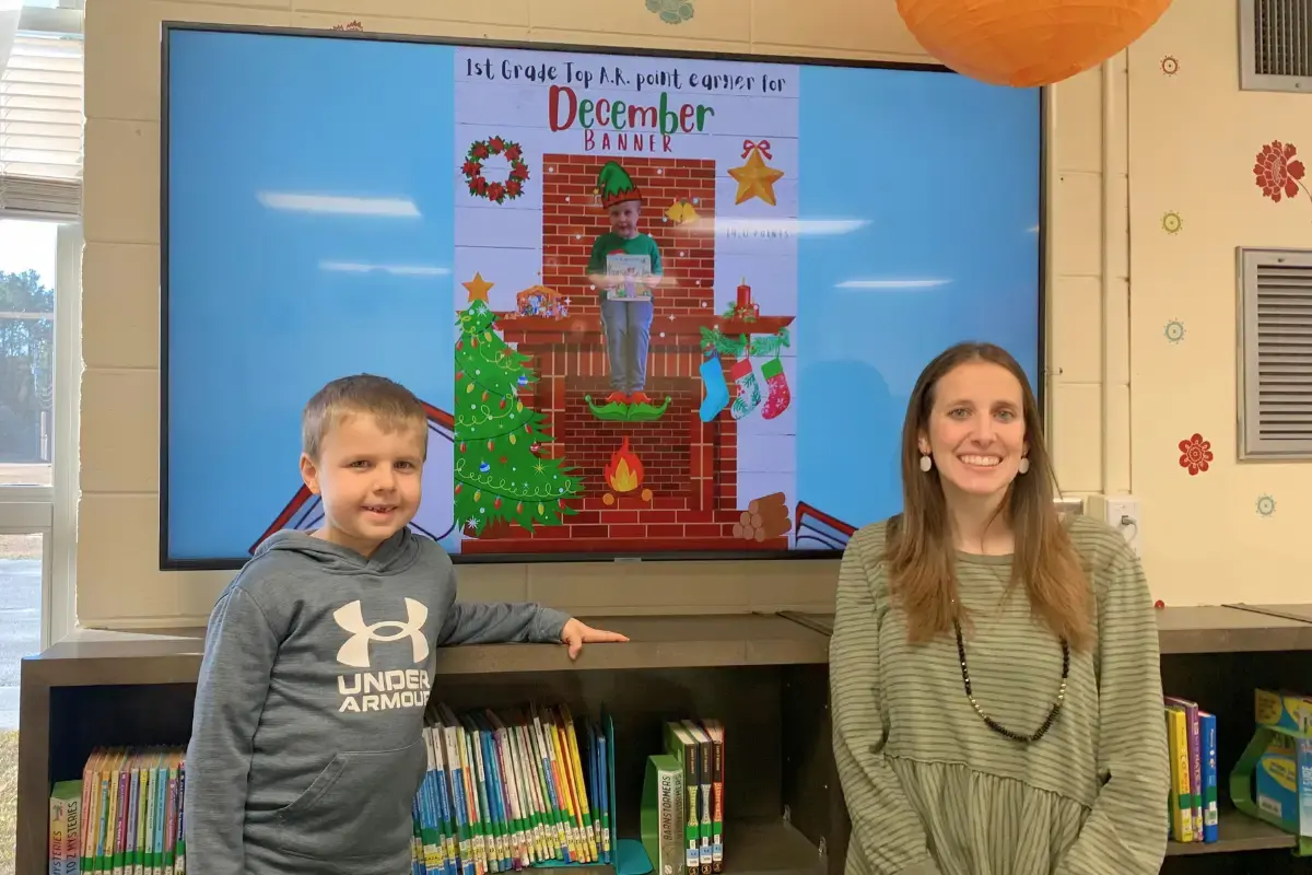 Kailee Rowell with a student in front of a digital signage display