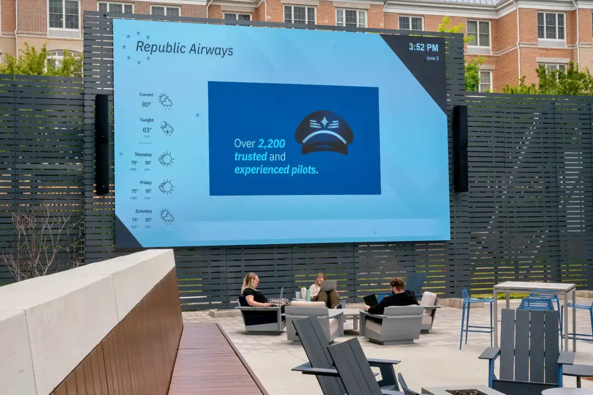Remote team with a large digital signage display as they sit in chairs and work