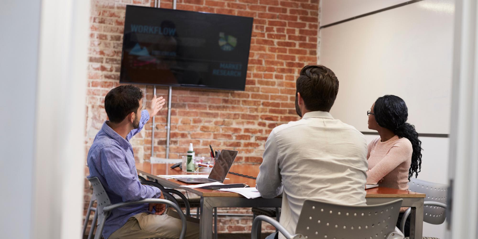 Office workers looking at the content on a digital signage screen.