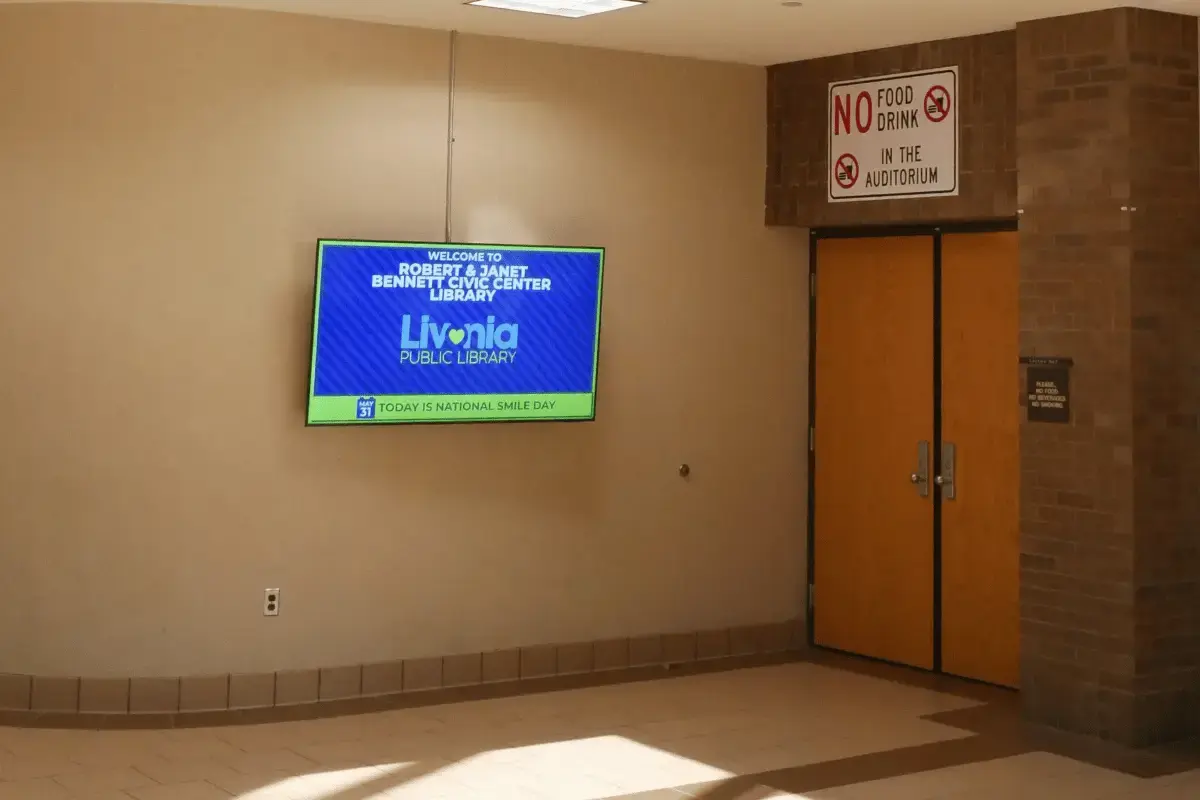 A large digital display signage near a pair of doors in a government facility