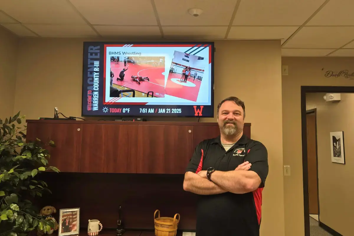 A teacher standing in front of a digital signage display