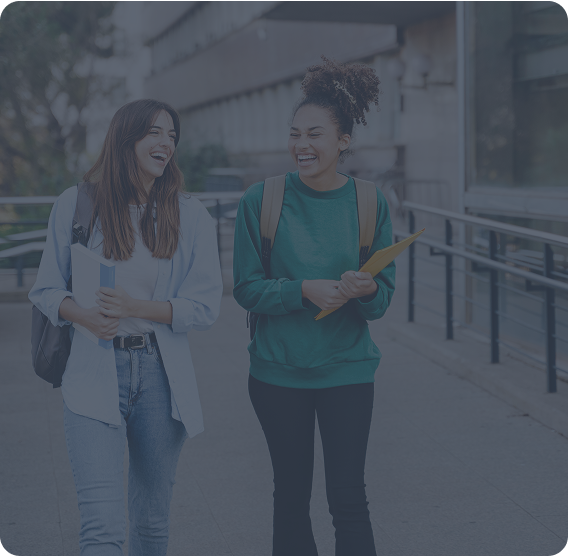 Two female college students walking and laughing on campus walkways