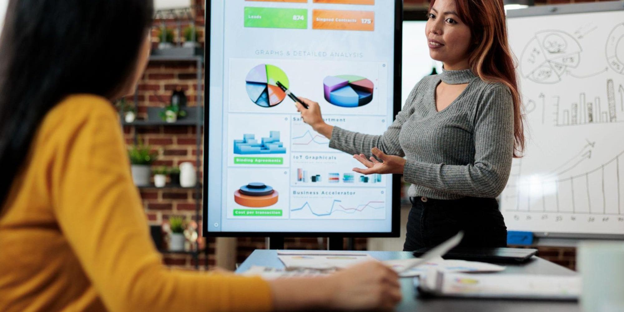 A sales professional discussing digital sales board data with a colleague.