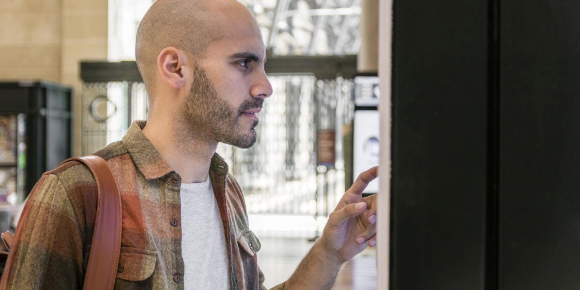 A man squinting his eyes while looking at a digital signage screen.