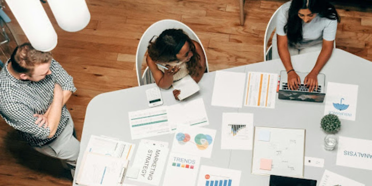 A group of employees collaborating around a table, fostering teamwork and knowledge sharing in the workplace.