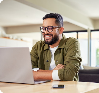 A south asian male sitting at a table and watching a demo of Rise Vision on his laptop