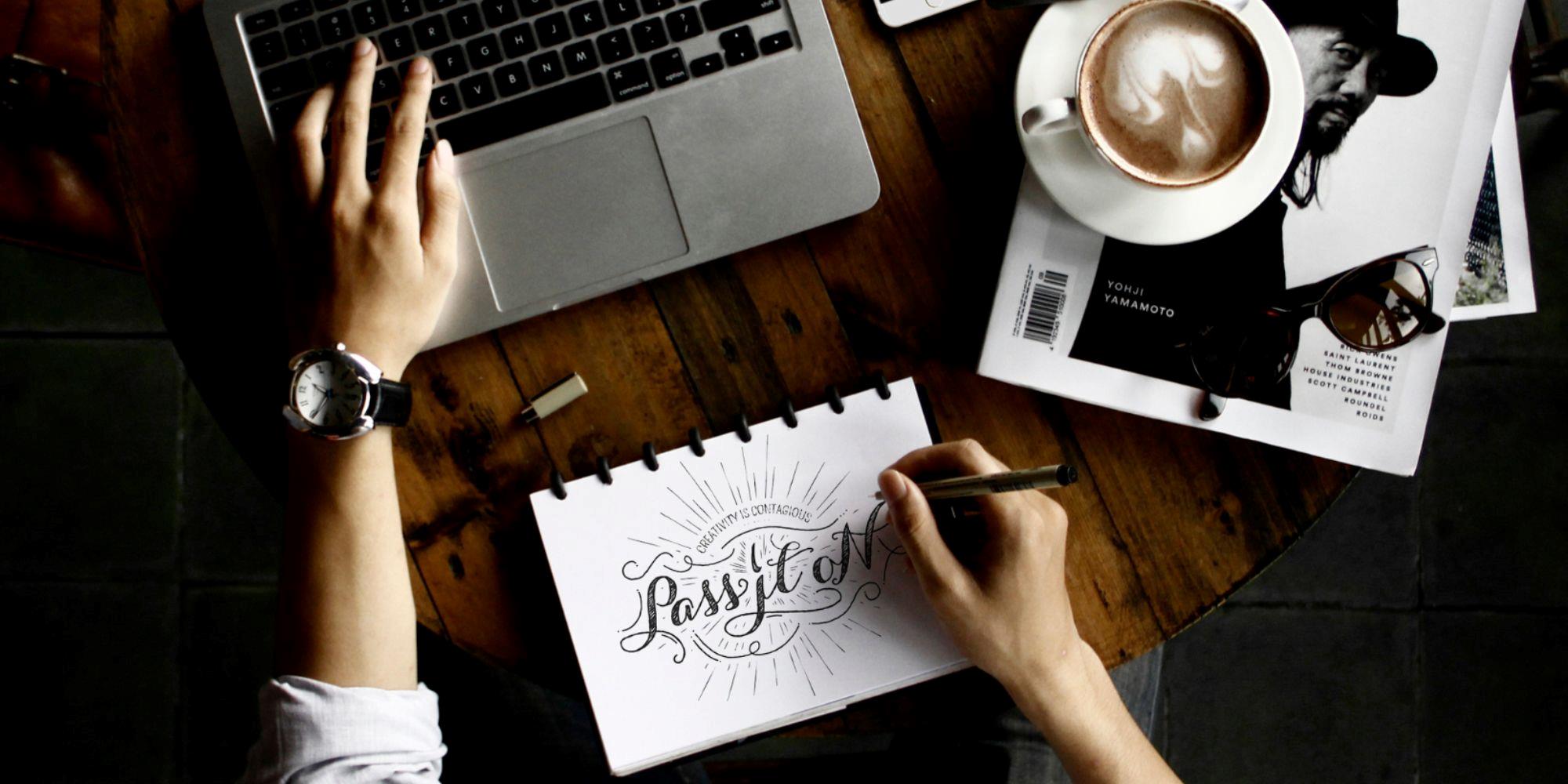 A person drawing a logo with unique typography on a notebook sheet to be used later for digital signage.