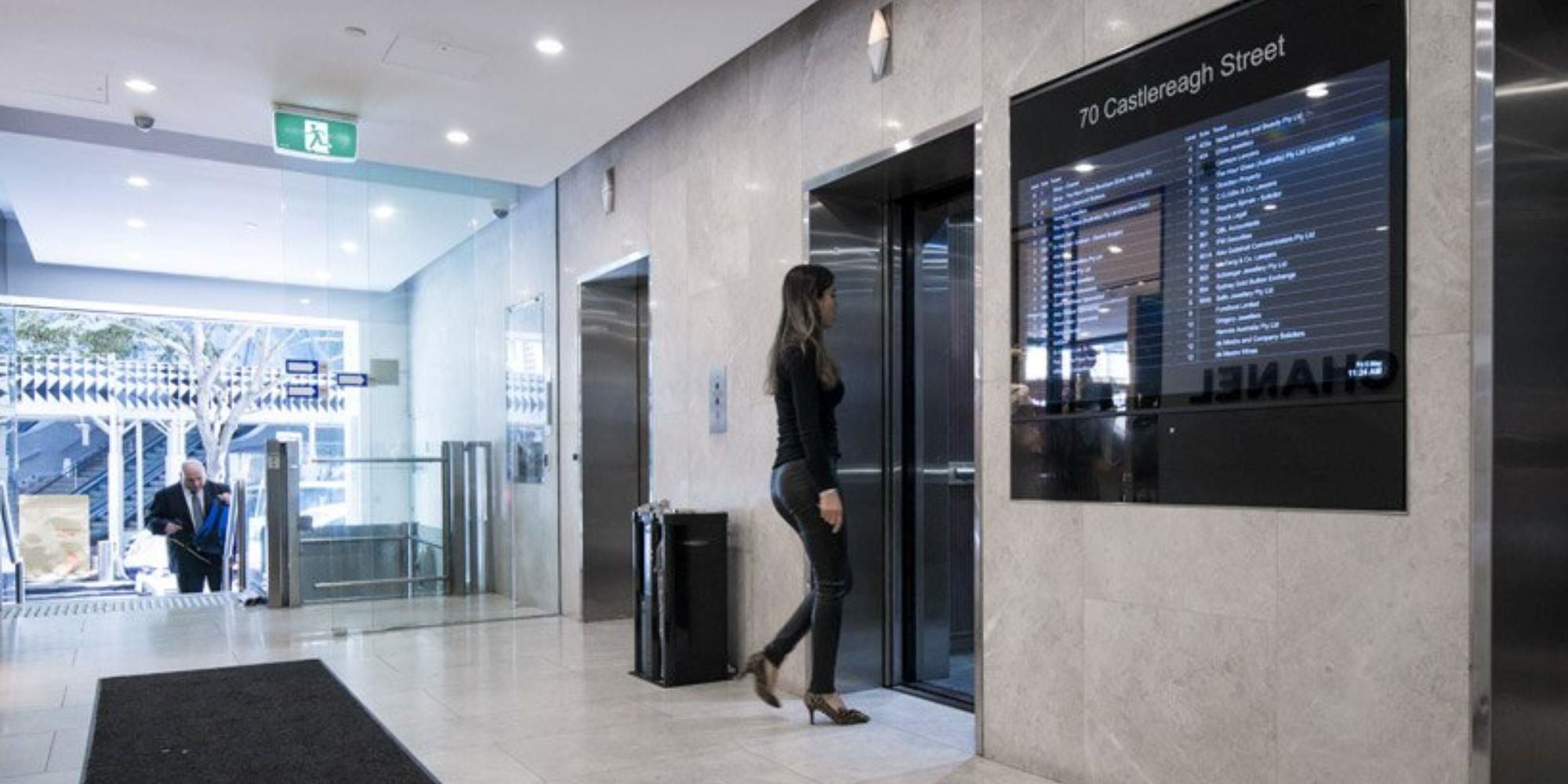  A woman walking past an Interactive building directory.