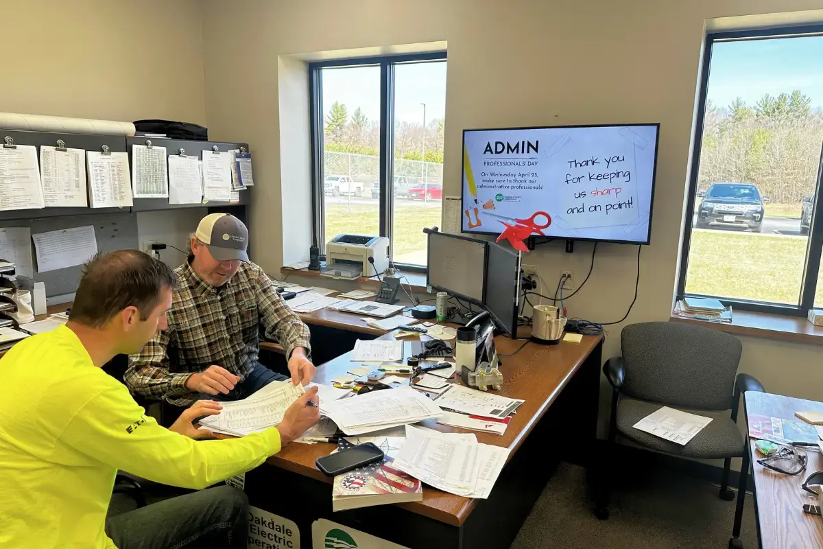 Two men speaking to each other with a Rise Vision digital signage display at the Oakdale Electric Cooperative office