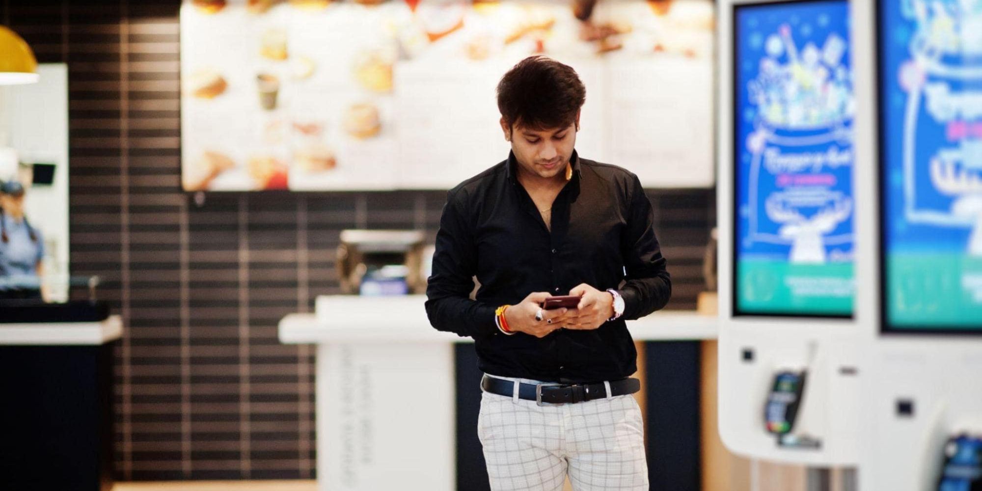 A man in a fast food restaurant filled with point of sale digital signage.