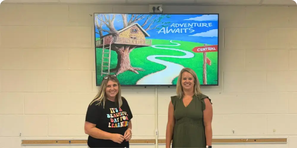 two teachers in front of a display